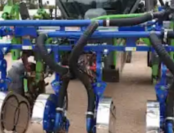 Gros plan sur un équipement agricole bleu avec tuyaux et roues métalliques.