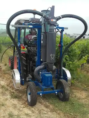 Machine agricole mobile avec tuyaux et moteur, utilisée pour le travail du sol entre rangs de vigne.