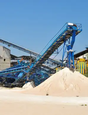 Convoyeurs industriels bleus transportant du sable dans une installation de traitement à ciel ouvert.