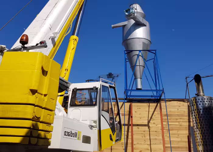 Nacelle élévatrice jaune près de conduits métalliques sur un chantier industriel.